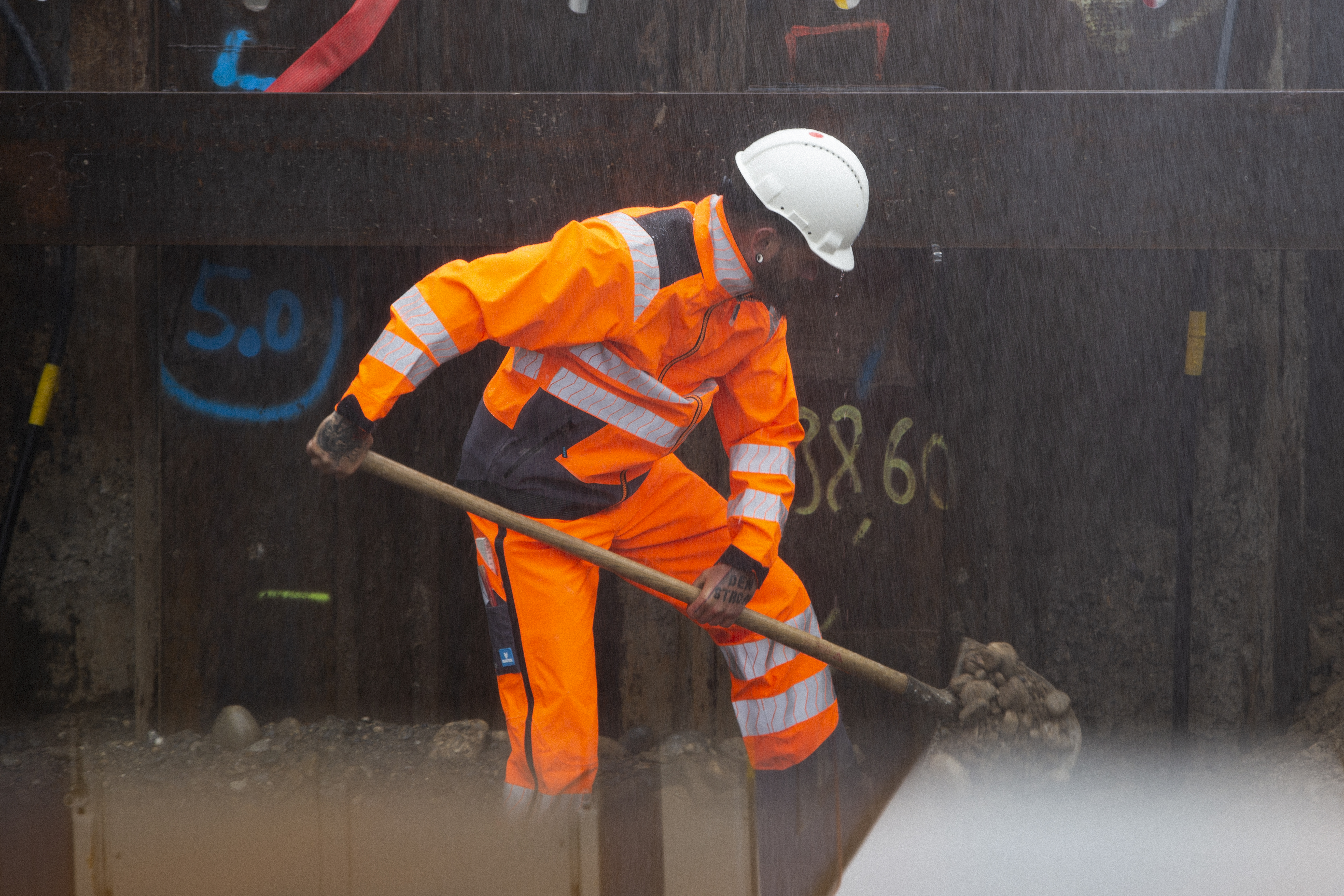 Ouvrier du bâtiment avec casque et vêtements de pluie avec bandes réfléchissantes